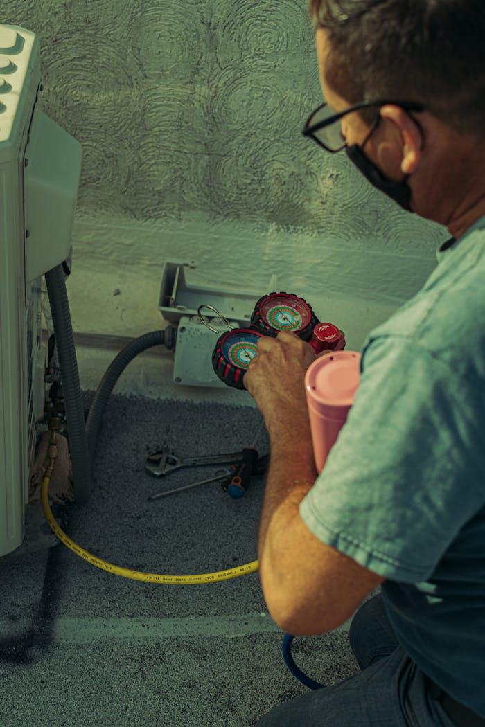 A technician checks and repairs an HVAC system outdoors using tools and gauges.